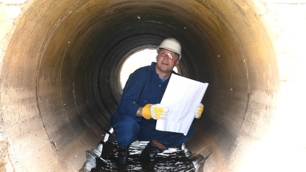 engineer inspecting large sewer pipe
